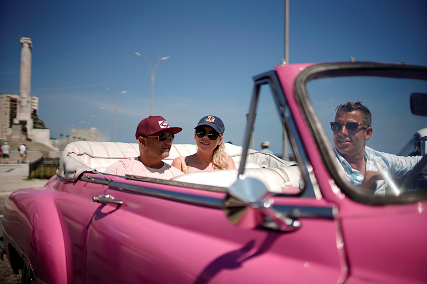 Американские туристы Аманда Пэрис и Михаэль Шумахер катаются на старинном автомобиле в Гаване