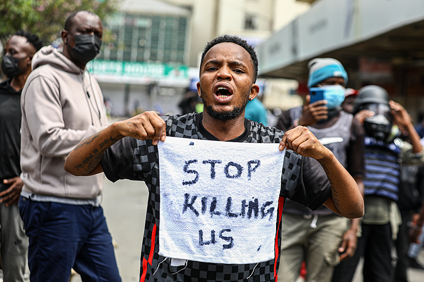 Мужчина держит в руках полотенце с надписью: "Хватит нас убивать" во время антиправительственных протестов в Найроби, 2 июля 2024 года