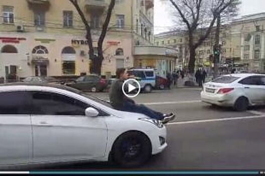 На видео попало, как в центре Воронежа парень катается на капоте машины