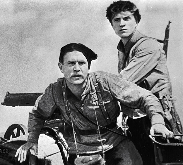 Актеры Борис Бабочкин (слева, в роли Чапаева) и Леонид Кмит (справа, в роли Петьки).  В основу легендарной киноленты о Гражданской войне лег одноименный роман Дмитрия Фурманова. Картина стала немыслимо популярной: за 15 дней со дня премьеры ее посмотрели более 2 миллионов советских кинозрителей. «Чапаев» держал в напряжении до последней минуты — а именно к этому и стремились режиссеры фильма Сергей и Георгий Васильевы. «Мы хотим волновать зрительный зал, мы хотим, чтобы наш зритель любил наших героев и ненавидел наших врагов», — писали они в газете «Известия». И действительно, зрители тяжело переживали гибель героев в финале «Чапаева».  Картину ждали многочисленные премии и международная известность, а ее актеров – по-настоящему огромная слава. В 1935 году на 1-м Московском международном кинофестивале «Чапаев» получил первую премию. В том же году картину объявили «Лучшим фильмом на иностранном языке» по версии Национального совета кинокритиков США. Кроме того, именно благодаря ленте в народ в таком масштабе пошли анекдоты про Чапаева и Петьку.