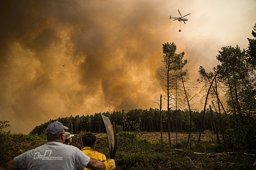 Жители Соутело-Верде в Ласе, провинция Оренсе, Испания, наблюдают за пожарным вертолетом, 17 августа 2025 года