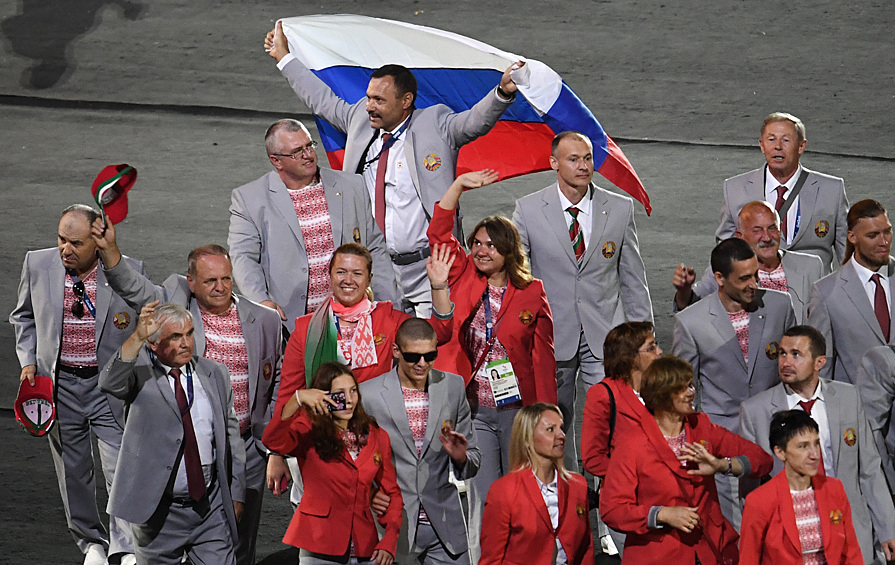 Директор "Республиканского центра олимпийской подготовки по легкой атлетике", представитель белорусской делегации Андрей Фомочкин (на дальнем плане) с флагом России во время парада атлетов и членов национальных делегаций на церемонии открытия XV летних Паралимпийских игр 2016 в Рио-де-Жанейро