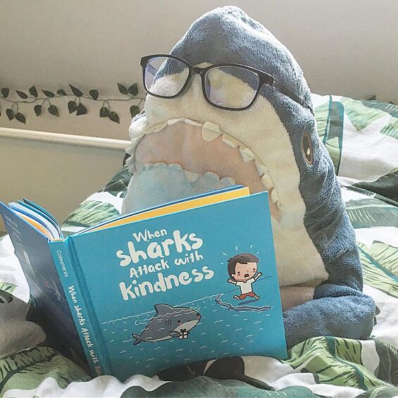 Акула Blahaj любит читать и даже носит очки.