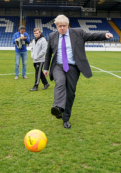 Премьер-министр Великобритании Борис Джонсон пинает футбольный мяч во время визита в клуб «Бери» на их стадионе в Гигг-лейн, Бери, Большой Манчестер, Великобритания, 25 апреля 2022 года
