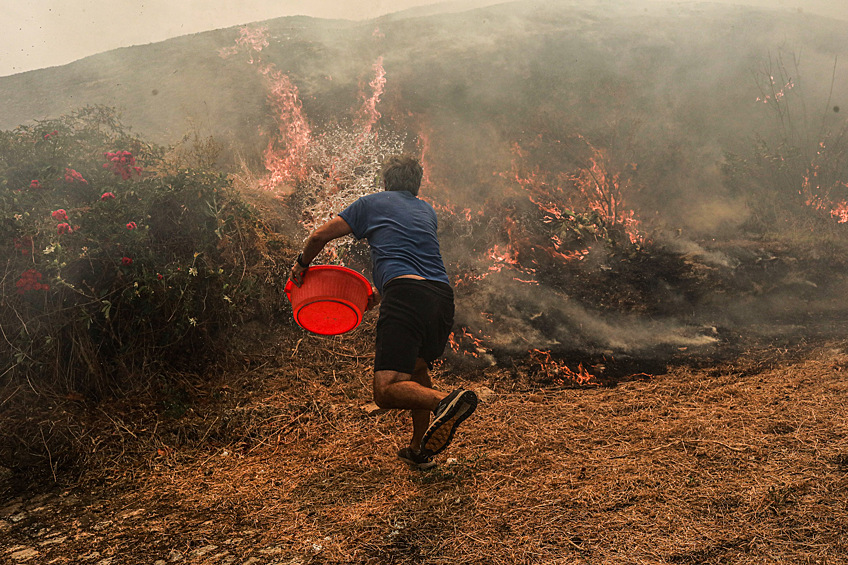 Местный житель пытается тушить лесной пожар в Вила-ду-Туру, Португалия, 16 августа 2025 года