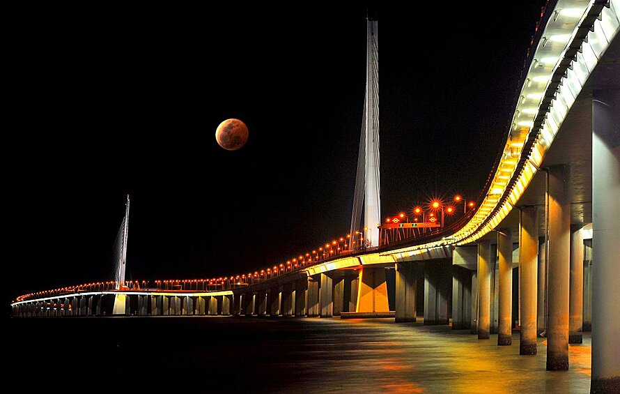 пециальный приз «Города: архитектура и пространства». Восходящая красная луна освещает мост через пролив в Шэньчжэне, Китай
