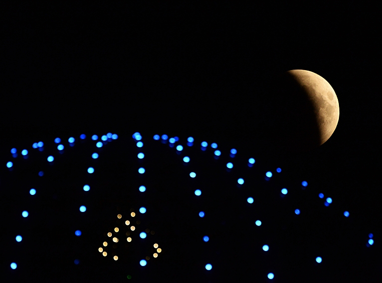 Луна во время затмения на фоне купола гостиницы высотного комплекса "Грозный сити" в Грозном