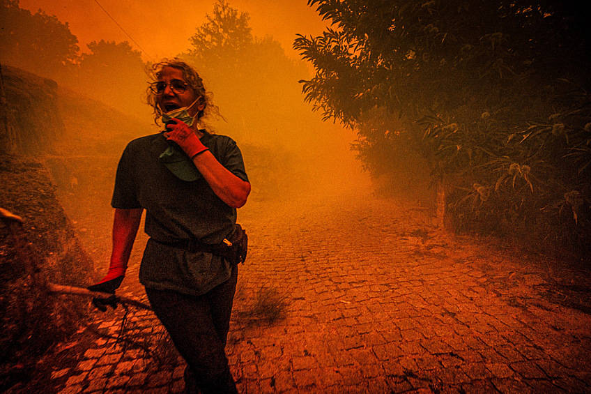 Женщина идет среди дыма лесного пожара в Масиейре, Португалия, 15 августа 2025 года