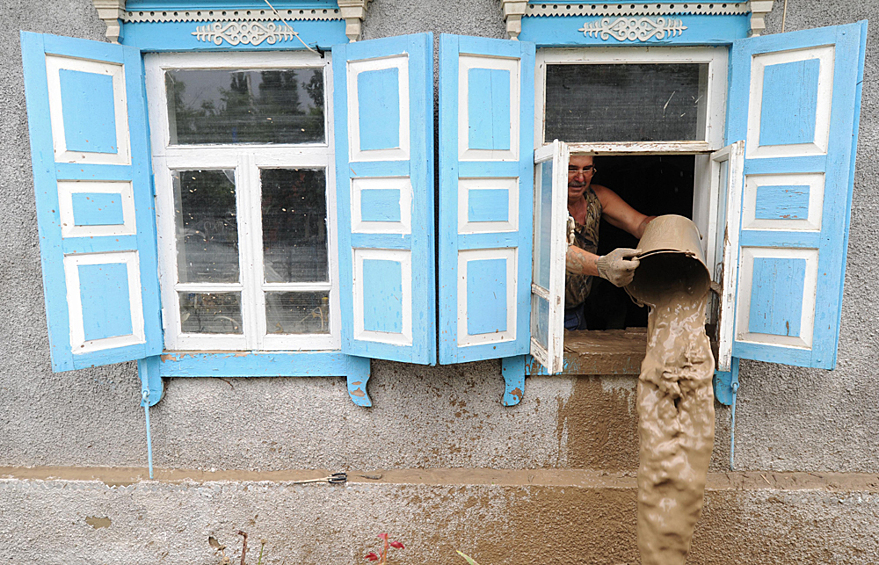 Мужчина вычерпывает воду из жилого дома, пострадавшего от наводнения в городе Крымск в Краснодарском крае