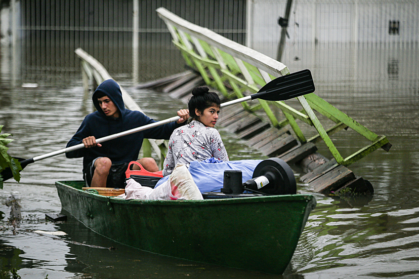 Люди спасаются на лодке в затопленном городе Порту-Алегри