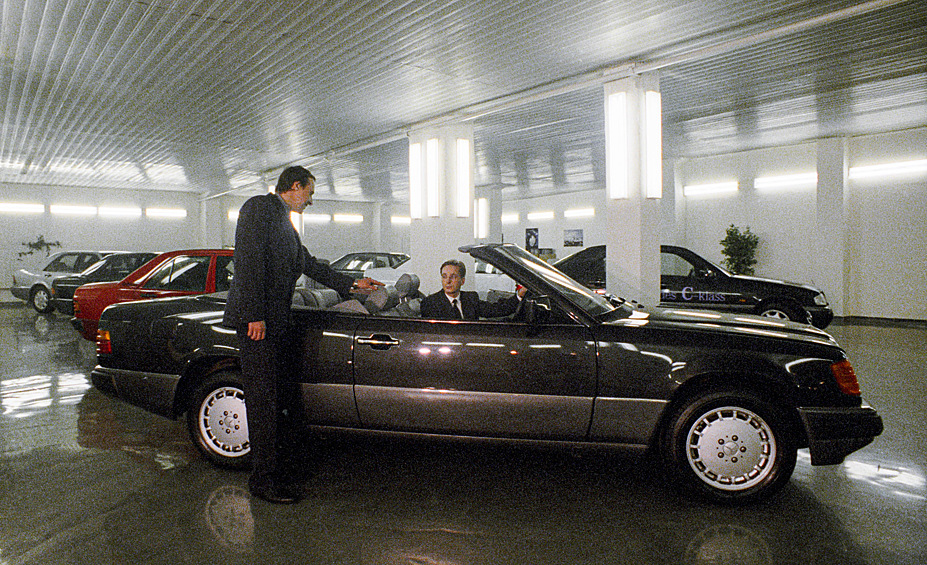 Небольшая прослойка населения, которую стали называть «новыми русскими», стремительно обогащалась. Символом достатка того времени стал автомобиль «Мерседес». Покупатели выбирают автомобиль марки Мерседес в автосалоне "ВИКО-Центр", 1993 год