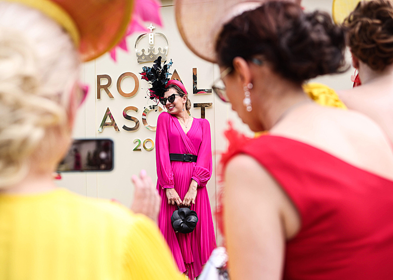 Посетительница скачек Royal Ascot позирует на камеру