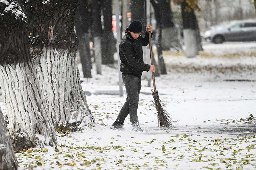 Дворник чистит дорогу во время снегопада в Москве