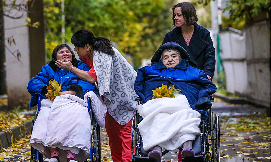 Медсестра Гуля и волонтер Софья Кузнецова с пациентками во время прогулки на территории Центра паллиативной медицины, 2016 год