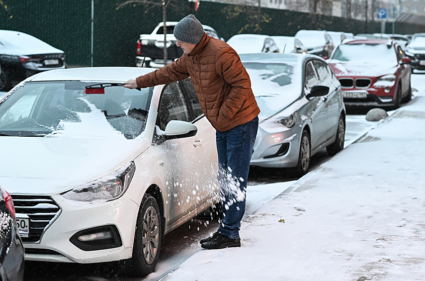 Мужчина расчищает автомобиль от снега в одном из дворов Москвы