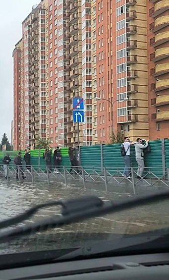 Жители Москвы пробираются через лужу