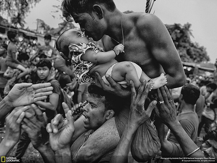 "Индуист целует своего новорожденного ребенка во время фестиваля Чарак Пуджа в Западной Бенгалии, Индия".
