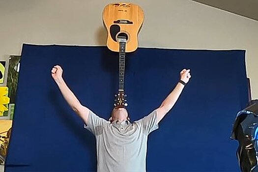 Мужчина полтора часа балансировал гитарой на подбородке и побил рекорд