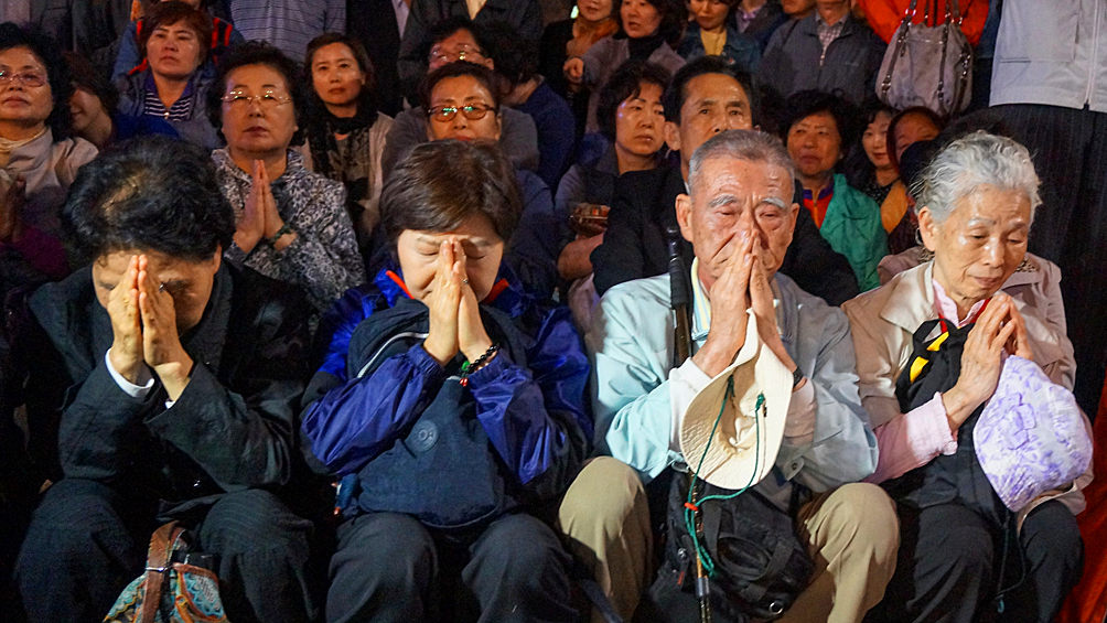 Люди молятся за погибших и пропавших без вести пассажиров перевернувшегося корабля «Севоль», 2014 год