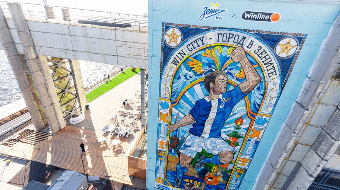 В Петербурге появился мурал в честь 100-летия «Зенита». Арт-объект сделан в виде витража с футболистом в ретро-форме и достопримечательностями города