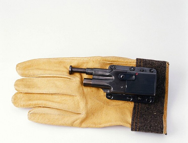 Изобретение принадлежит американскому ВМФ периода Второй мировой. Пистолет позволял агенту поразить врага, даже не снимая перчаток. Выстрел производился в упор, когда поршень на дуле прижимался к телу жертвы.