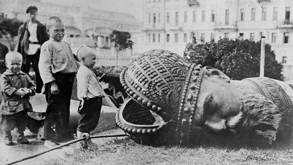Оторванная голова памятника Александру III в Москве во время его разрушения.  Ленин вдохновился идеями итальянского философа-утописта Томмазо Кампанеллы – автора знаменитого «Города Солнца», написанного в начале XVII века.  «Вы помните, что Кампанелла в своем «Солнечном государстве» говорит о том, что на стенах его фантастического социалистического города нарисованы фрески, которые служат для молодежи наглядным уроком по естествознанию, истории, возбуждают гражданское чувство — словом, участвуют в деле образования, воспитания новых поколений. <...> Пожалуйста, не думайте, что я при этом воображаю себе мрамор, гранит и золотые буквы. Пока мы должны все делать скромно», – добавил Ленин.  Сказано – сделано. Отдел изобразительных искусств Наркомпроса должен был составить списки памятников, подлежащих сносу («в честь царей и их слуг»), устроить конкурс памятников «в ознаменование великих дней Российской социалистической революции», поменять старые гербы, названия улиц и так далее – чтобы отразить «идеи и чувства революционной России». И, наконец, к Первомаю украсить Москву.  Декрет к нужному сроку выполнен не был из-за организационной путаницы и волокиты. Только Кремль обмотали красным кумачом и задрапировали старые русские символы.  Перед тем, как ставить новые памятники, было решено сбросить старые – чтобы народ не путался и понимал, кто теперь власть. Был разрушен памятник Александру III – его, по сути, четвертовали, демонтировав огромную металлическую голову в царской короне и отделив другие части «тела» статуи. Процесс засняли на киноаппарат и крутили по синематографам всей страны.