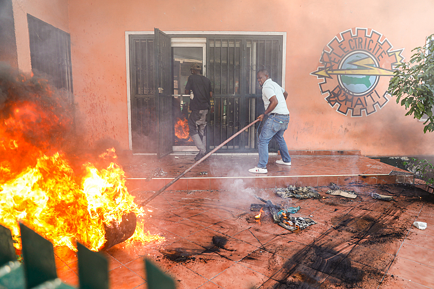 Рабочие тушат пожар в офисе энергетической компании Гаити во время акции протеста с требованием отставки премьер-министра Ариэля Генри