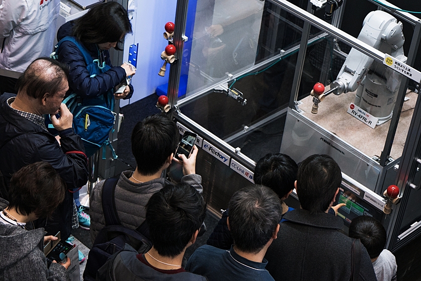Посетители международной выставки роботов IREX в Токио у робота RV-4FRL-R, запрограммированного на традиционную японскую игру Кэндама.