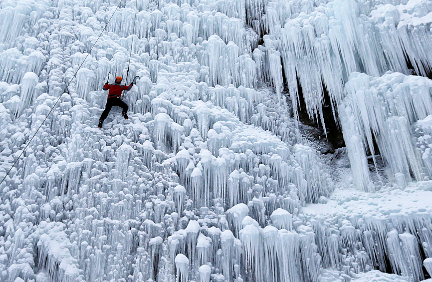 Скалолаз на искусственной ледяной стене в городе Либерец, Чехия