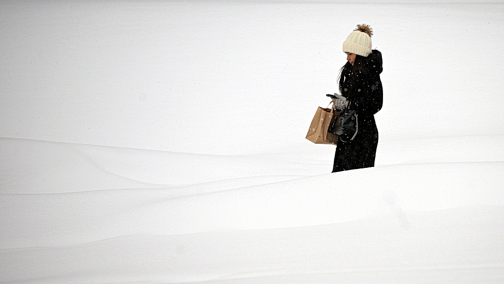 Девушка идет на фоне сугробов в Москве. Столичный регион накрыл мощный атмосферный фронт