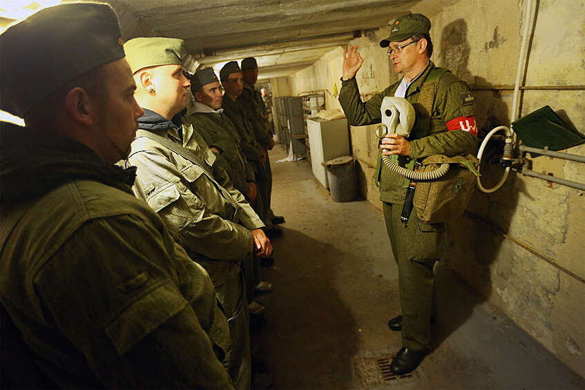Сотрудник музея «Фрауэнвальд» в форме сержанта армии ГДР объясняет посетителям, как пользоваться противогазом