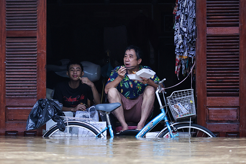 Местные жители у затопленного дома в городе Хойане