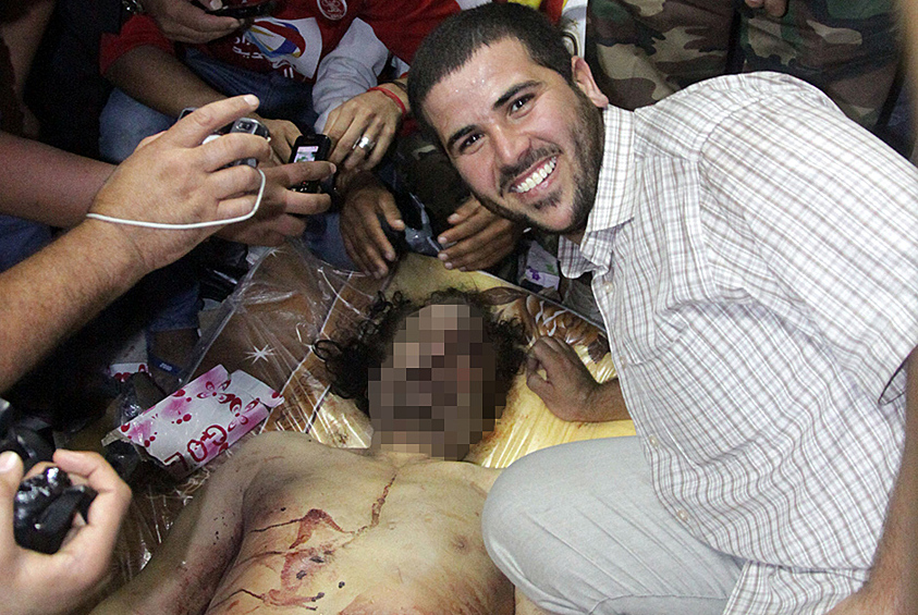 Ливийцы фотографируются рядом с телом бывшего лидера страны Муаммара Каддафи
