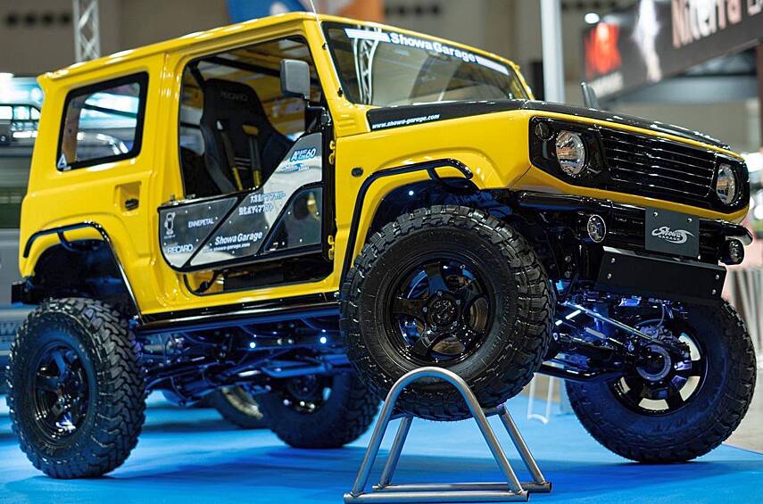 Микровнедорожничек Suzuki Jimny, подготовленный мастерской Showa Garage для джип-триала. Колёса M/T внешним диаметром 31,7 дюйма — для такой крохи это огромный размер. В подвеске установлены длинные пружины и амортизаторы собственной разработки, в мостах — блокировки ARB с пневматическим включением. Внутри смонтирован каркас безопасности, а все двери демонтированы — вместо них простые «калитки» из труб. И всё это приводит штатный моторчик объёмом всего 660 «кубиков», мощность которого чипом довели до 98 л.с.