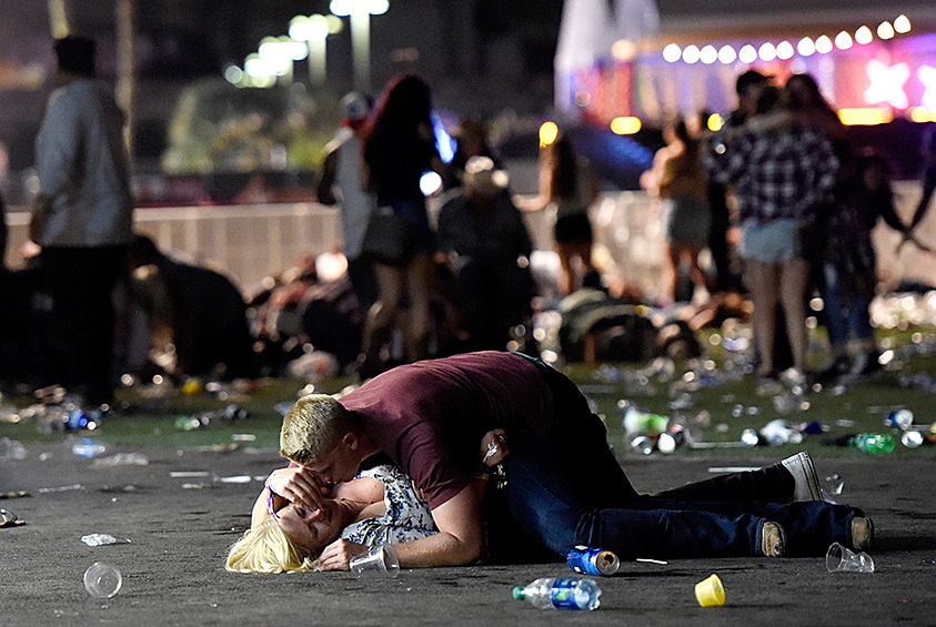 Мужчина прикрывает своим телом женщину на месте массового убийства в Лас-Вегасе. Стрельба была открыта в толпе на кантри-фестивале, в результате чего были убиты 59 человек, еще 527 получили ранения