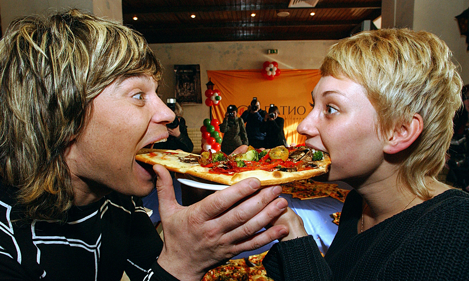 Солист группы "На-На" Вячеслав Жеребкин и пиар-менеджер Юлиана Шепелева едят пиццу, из которой была выложена самая большая в мире карта Италии в ресторане "IL Патио", 2004 год
