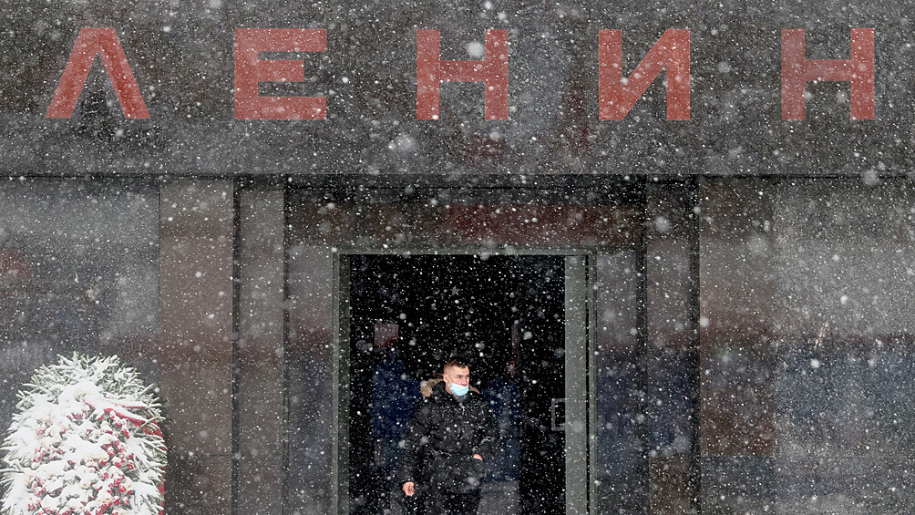 Мужчина у мавзолея Ленина на Красной площади во время снегопада в Москве, 7 декабря 2021 года
