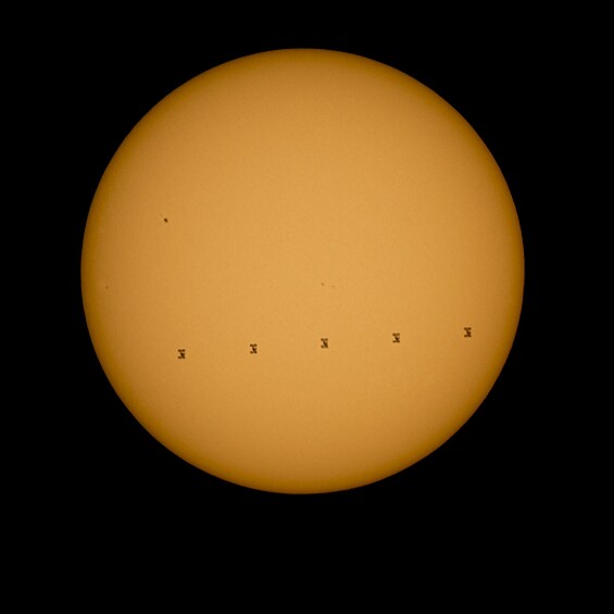 На изображении, составленном из пяти разных снимков, можно увидеть силуэт МКС, которая движется со скоростью 8 километров секунду, на фоне Солнца