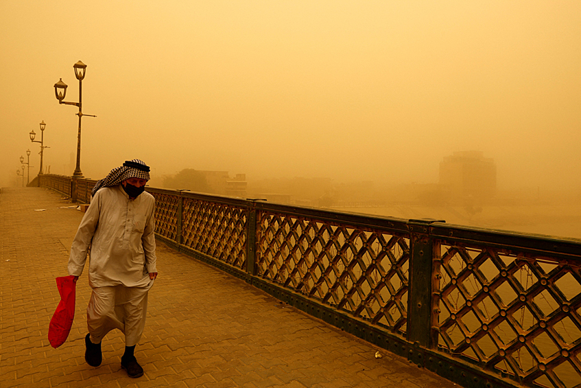 Мужчина идет по мосту во время песчаной бури в Багдаде