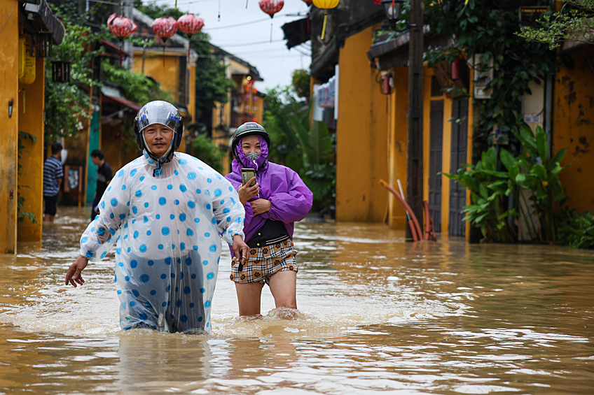 Местные жители идут по затопленной улице в городе Хойане