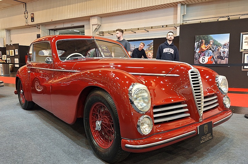 Прекрасное купе Alfa Romeo 6C 2500 Freccia d'Oro — дорогой и мощный «Гран-Туризмо» 1947 года выпуска: первая послевоенная модель Alfa Romeo, которую собирали прямо в цехах пострадавшего от бомбёжек завода в Портелло. Впрочем, в основе её лежит конструкция ещё 1938 года. Шасси — с простой лонжеронной рамой и независимыми подвесками, типа «Дюбонне» спереди и c качающимися полуосями сзади. Под капотом рядная «шестёрка» конструкции Витторио Яно объёмом 2,5 литра с двухвальной головкой, в версии с одним карбюратором выдававшая 90 л.с., что позволяло разгоняться до 155 км/ч. Кузов модицикации Freccia d'Oro изготовлен на самом заводе Alfa Romeo и жёстко приварен к раме — в отличие от довоенных версий, где кузов делали сторонние ателье, и он крепился к раме на болтах. После войны было сделано 2500 машин этой модели, из них 680 — версии Freccia d'Oro. Этот конкретный экземпляр выделяется сохранностью: до нашего времени дошёл и оригинальный мотор, и почти весь салон!