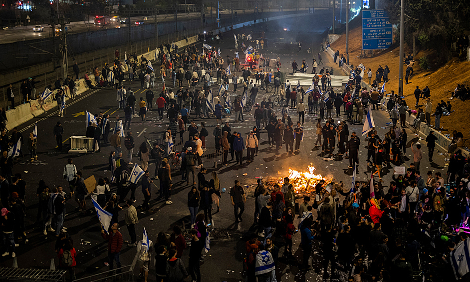 Израильские демонстранты блокируют дорогу во время протестов, 27 марта 2023 года
