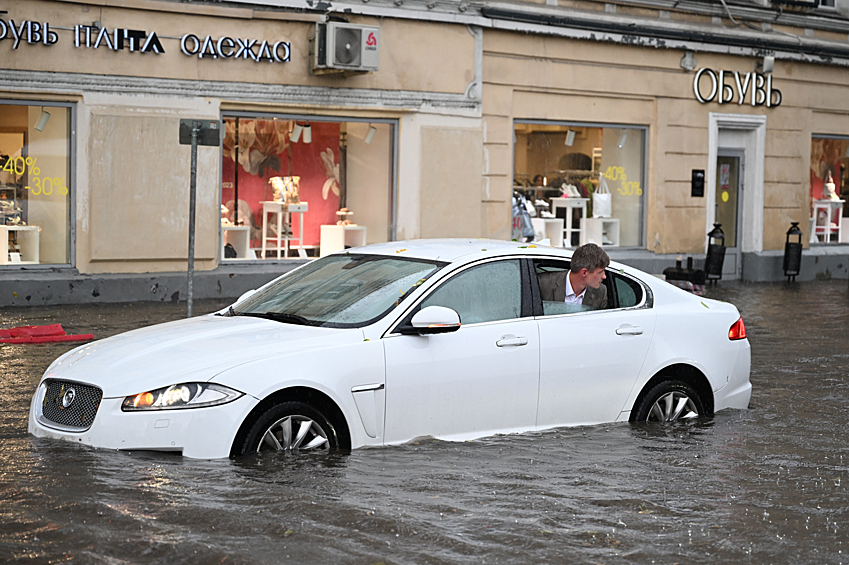 Автомобиль на подтопленной улице в результате ливня в Москве, июль 2023 года