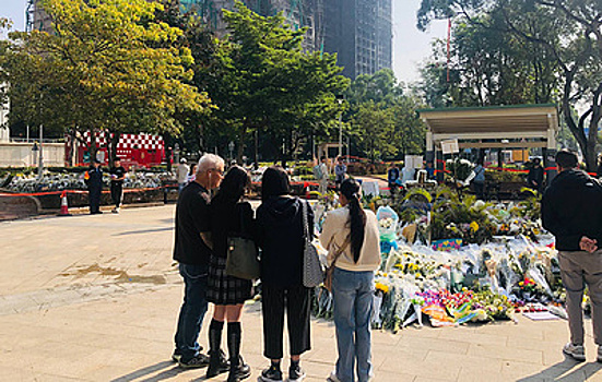 Жители Гонконга приносят цветы к сгоревшему комплексу