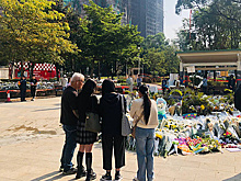 Жители Гонконга приносят цветы к сгоревшему комплексу