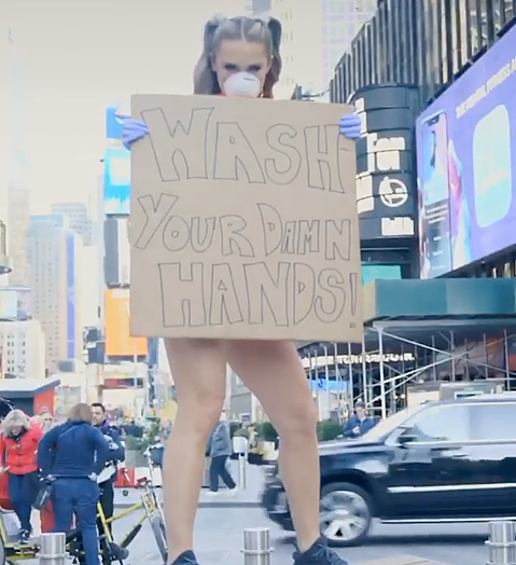 В руках девушка держала плакат с надписью: «Мойте свои чёртовы руки».