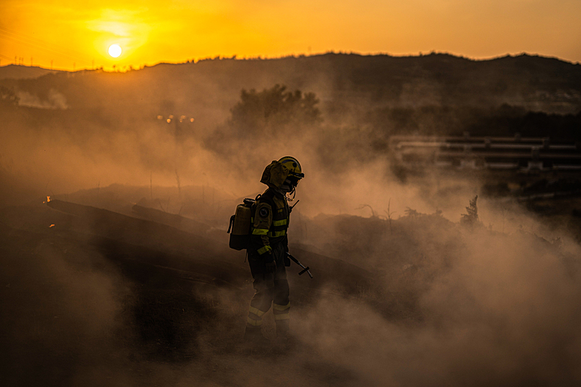 Пожарный пытается взять под контроль пламя во время лесного пожара в Монтеррее, Испания, 13 августа 2025 года