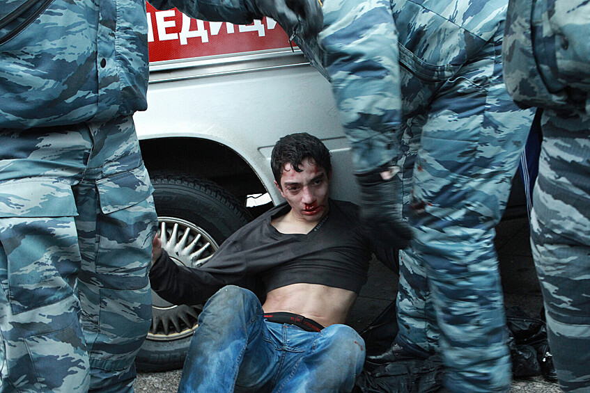 Сотрудники ОМОНа защищают молодого человека от участников акции в память об убитом фанате «Спартака» Егоре Свиридове, 11 декабря 2010 года