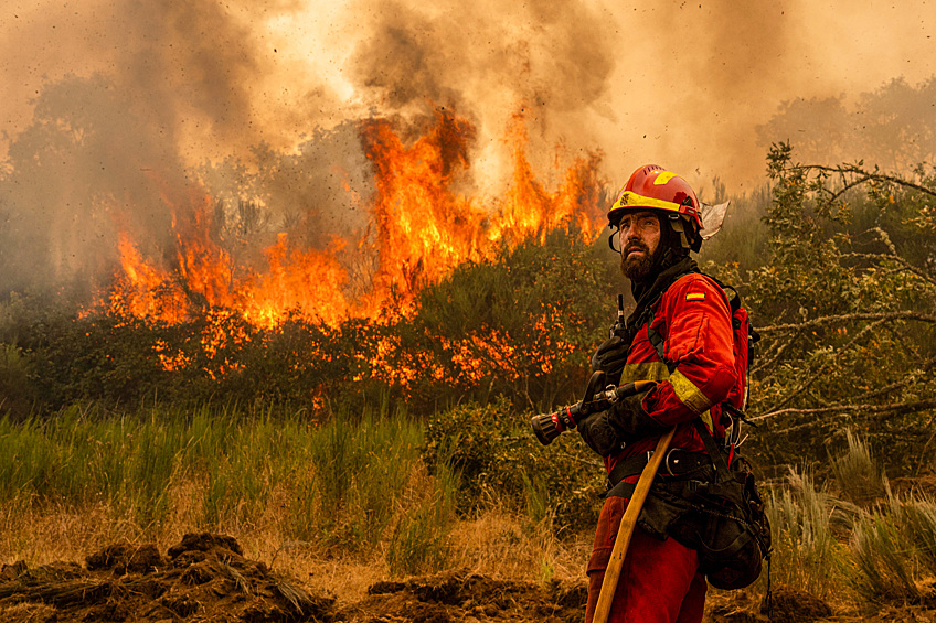 Сотрудник военного подразделения по чрезвычайным ситуациям тушит лесной пожар недалеко от города А-Эспаса, Испания, 12 августа 2025 года