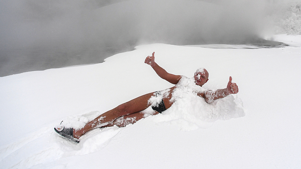 Член клуба зимнего плавания "Криофил" лежит в снегу после купания в Енисее при морозе около -30 градусов
